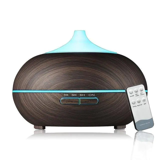 A wooden Essential Oil Aroma Diffuser with a blue light at the top, accompanied by a remote control.